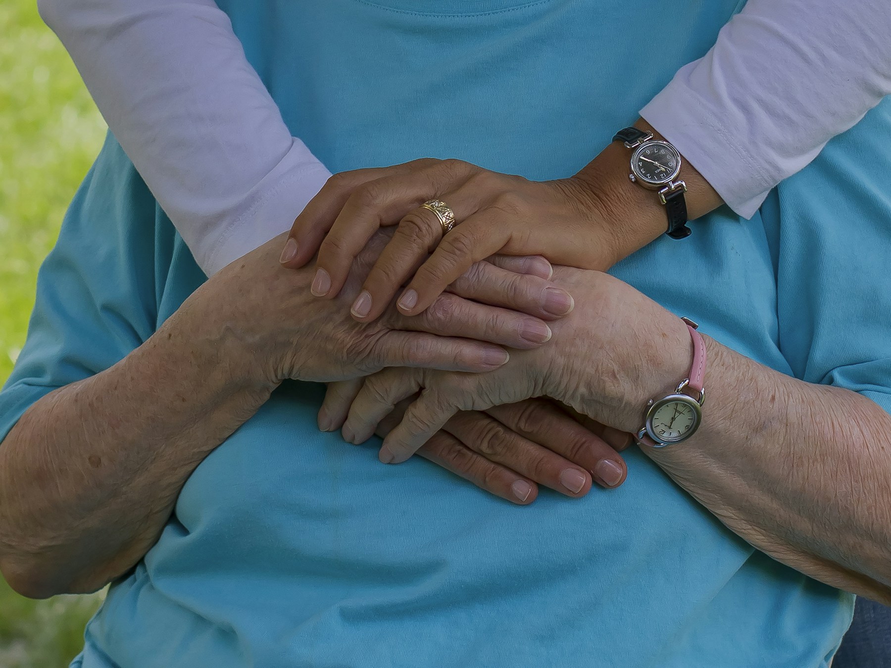 A caregiver gently placing their hands over an older adult's hands